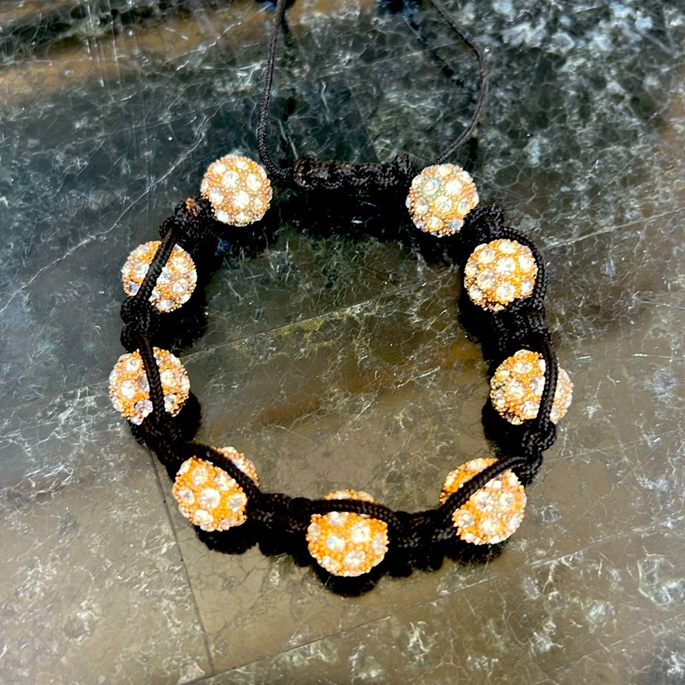 Women’s black bracelet, opens and closes with pull of string.